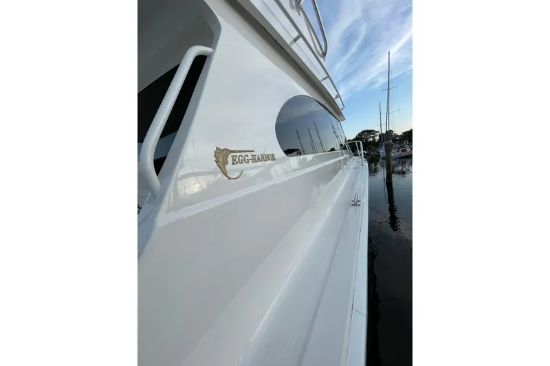 Slide: The Image of 2003 Egg Harbor 37 Sport Fisher yacht docked, showcasing sleek white exterior and logo. - 37