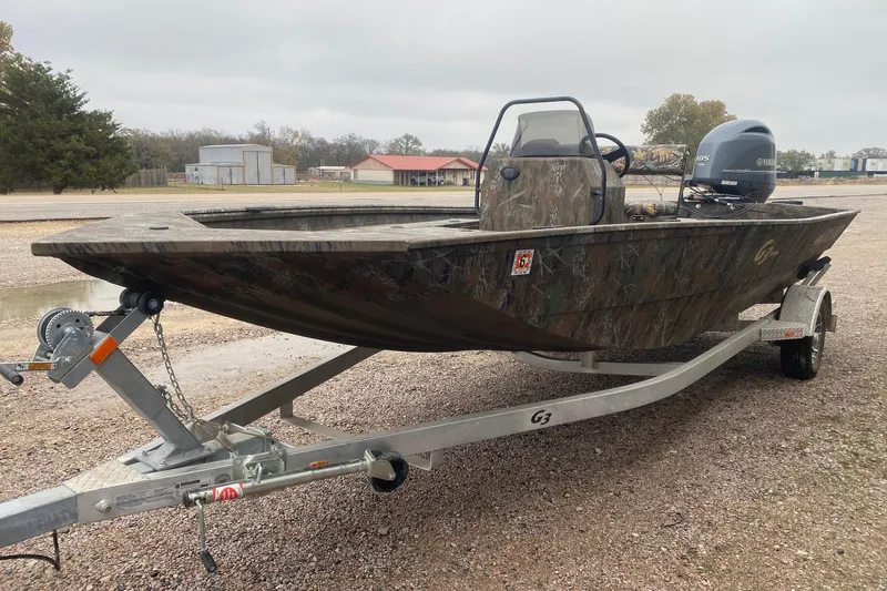 Slide: The Image of 2025 G3 Gator Tough 20 CCJ boat on trailer, camo design, parked outdoors. - 3