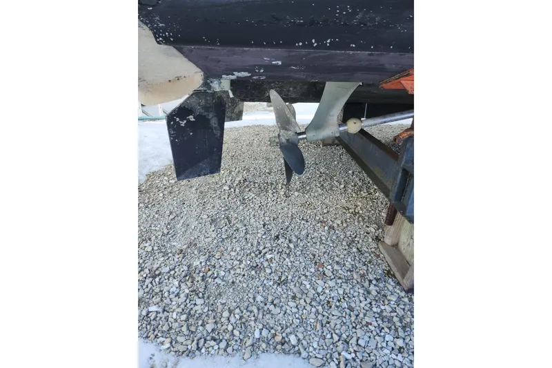 Slide: The Image of 1999 Maxum 3700 SCR boat propeller and rudder on gravel surface. - 10