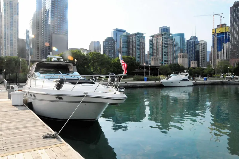 Slide: The Image of 1999 Maxum 3700 SCR yacht docked in urban marina with city skyline backdrop. - 2