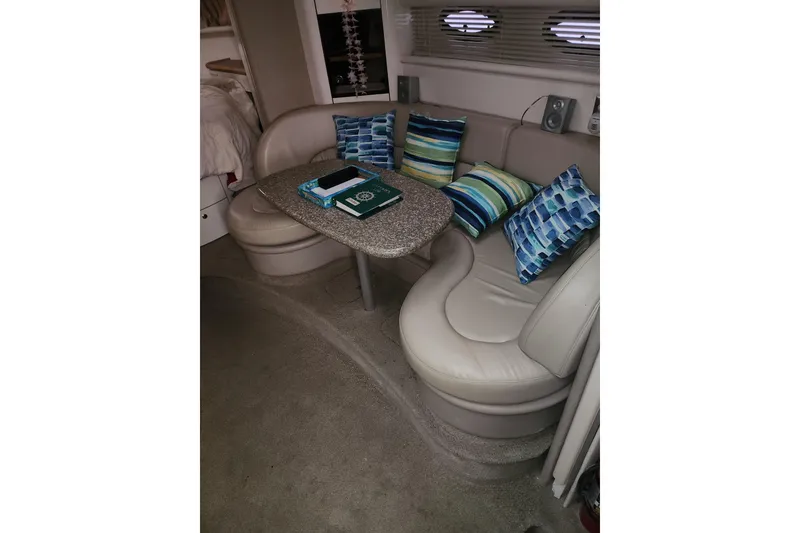 Slide: The Image of 1999 Maxum 3700 SCR yacht interior with cozy seating, striped cushions, and a small table. - 6