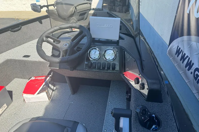 Slide: The Image of 2026 Lund 1650 Rebel XL SS boat dashboard with steering wheel and Simrad display. - 13