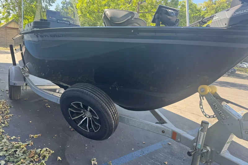 Slide: The Image of 2026 Lund 1650 Rebel XL SS boat on trailer, parked outdoors with trees in background. - 5