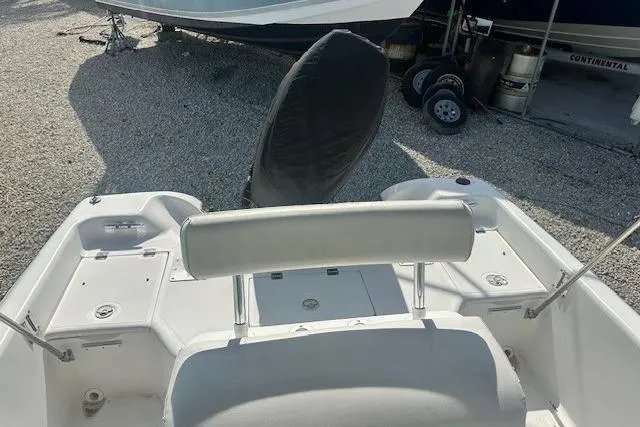 Slide: The Image of 1999 Mako Pro Skiff 21 CC boat interior with covered motor, parked on gravel. - 9