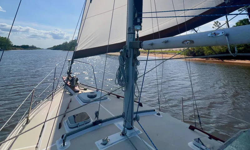Slide: The Image of 1986 Cape Dory MS300 sailboat navigating a scenic river under clear skies. - 10