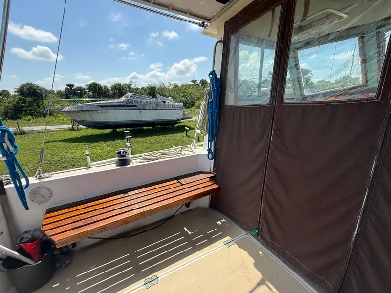 Slide: The Image of 1986 Cape Dory MS300 boat interior with wooden bench, outdoor view, and moored vessel. - 13