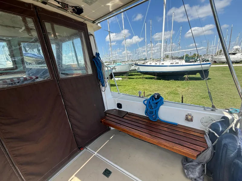 Slide: The Image of 1986 Cape Dory MS300 boat interior with wooden bench, docked near sailboats. - 14