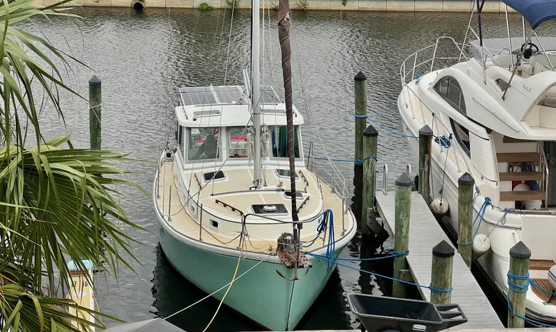 Slide: The Image of 1986 Cape Dory MS300 sailboat docked in a marina, surrounded by water and other boats. - 2