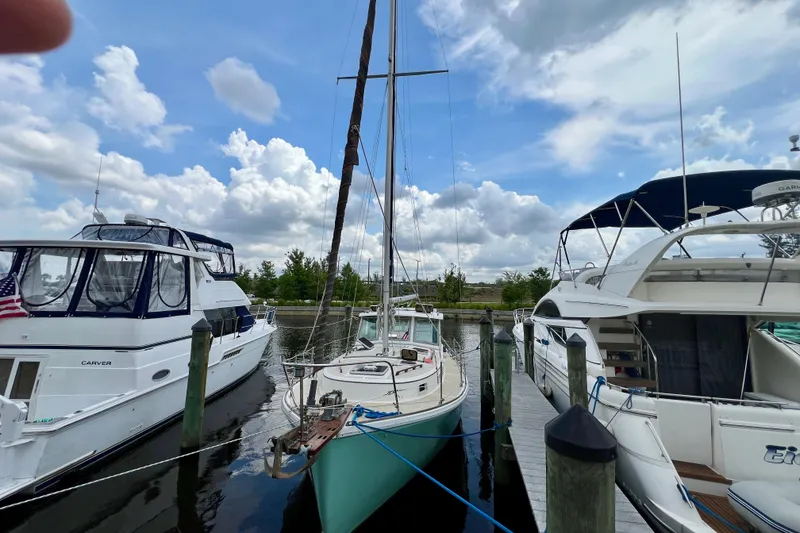 Slide: The Image of 1986 Cape Dory MS300 sailboat docked between two yachts under a cloudy sky. - 3