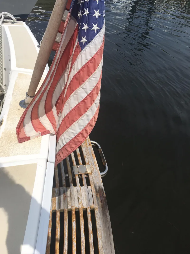 Slide: The Image of 1986 Cape Dory MS300 boat with American flag, docked by water. - 33
