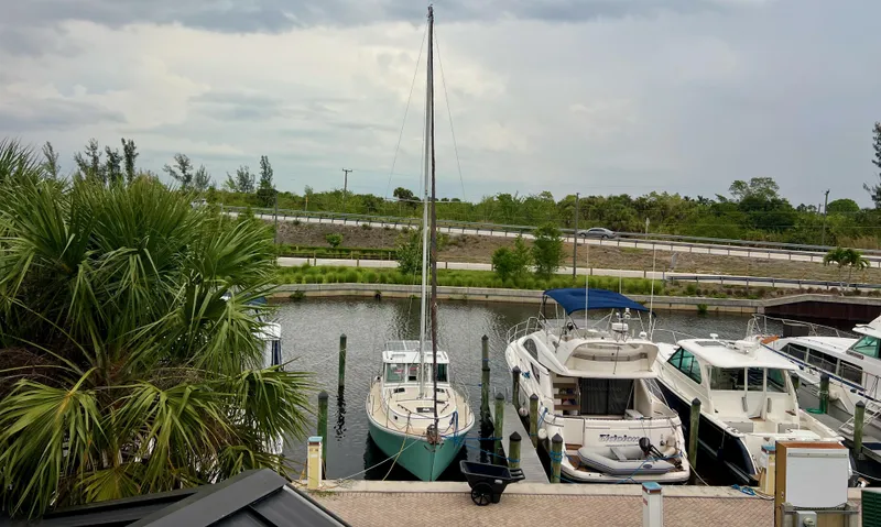 Slide: The Image of 1986 Cape Dory MS300 sailboat docked in a marina, surrounded by other boats and lush greenery. - 4