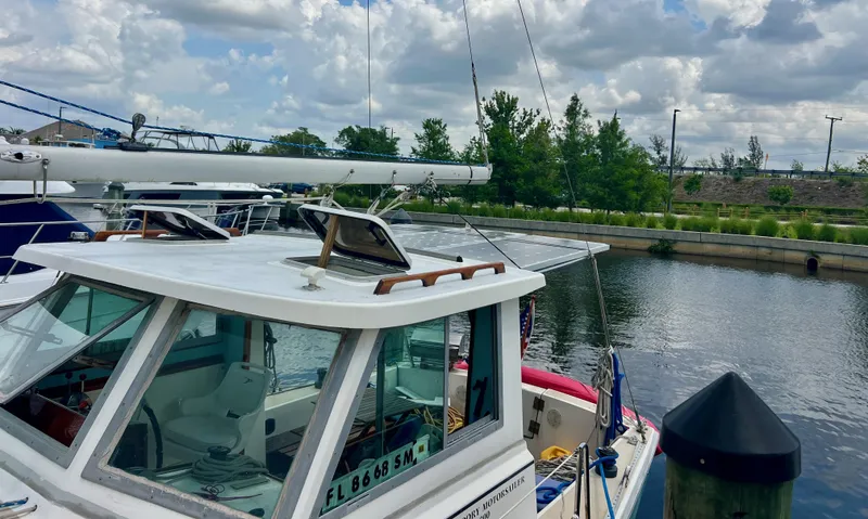 Slide: The Image of 1986 Cape Dory MS300 boat docked by a calm river under a cloudy sky. - 5