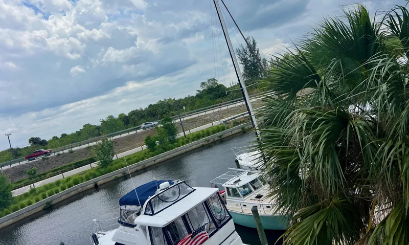Slide: The Image of Boats docked by a canal with a Cape Dory MS300, 1986 model, under a cloudy sky. - 77