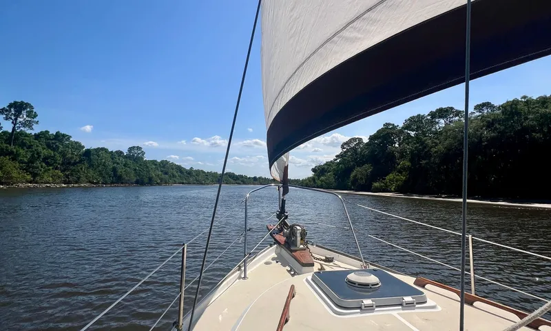 Slide: The Image of 1986 Cape Dory MS300 sailboat navigating a serene river under clear blue skies. - 8