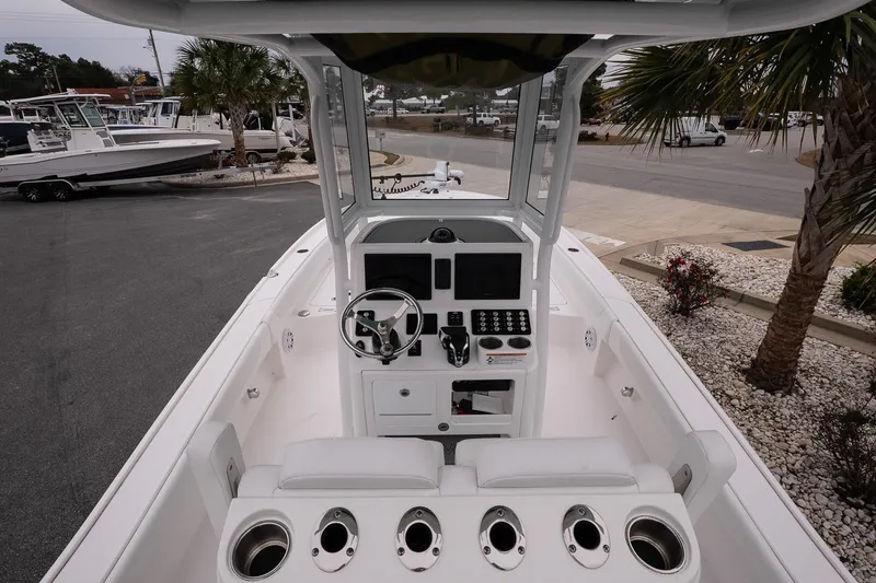 Slide: The Image of 2025 Caymas 26 HB boat interior with modern helm and seating, parked outdoors. - 10