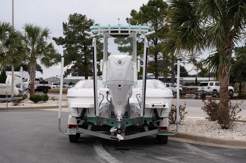 Slide: The Image of 2025 Caymas 26 HB boat on trailer, parked near palm trees. - 6