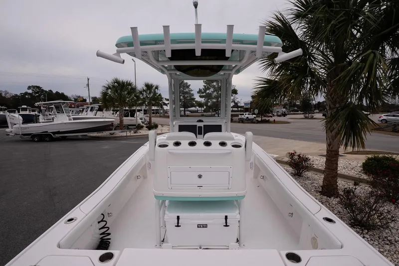 Slide: The Image of 2025 Caymas 26 HB boat interior with T-top and console, parked near palm trees. - 8