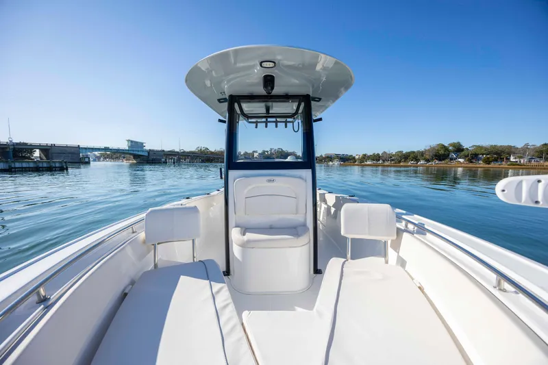 Slide: The Image of 2024 Sea Hunt Ultra 239 SE boat on calm water, showcasing sleek design and spacious seating. - 12
