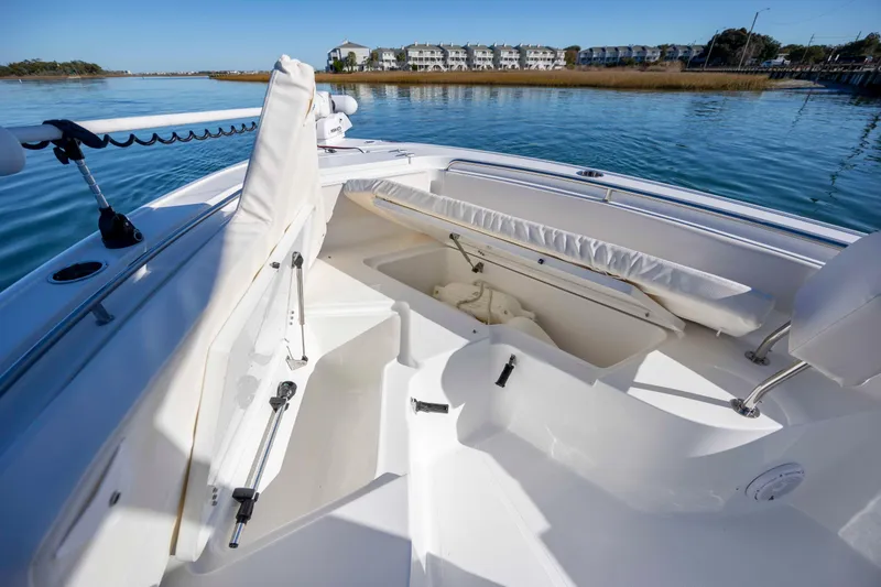 Slide: The Image of 2024 Sea Hunt Ultra 239 SE boat interior with open storage compartments on calm water. - 14