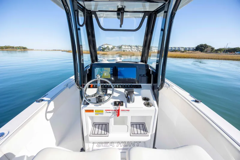 Slide: The Image of 2024 Sea Hunt Ultra 239 SE boat cockpit with modern navigation system on calm water. - 17