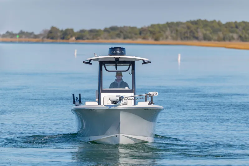 Slide: The Image of 2024 Sea Hunt Ultra 239 SE boat cruising on calm water with scenic background. - 7