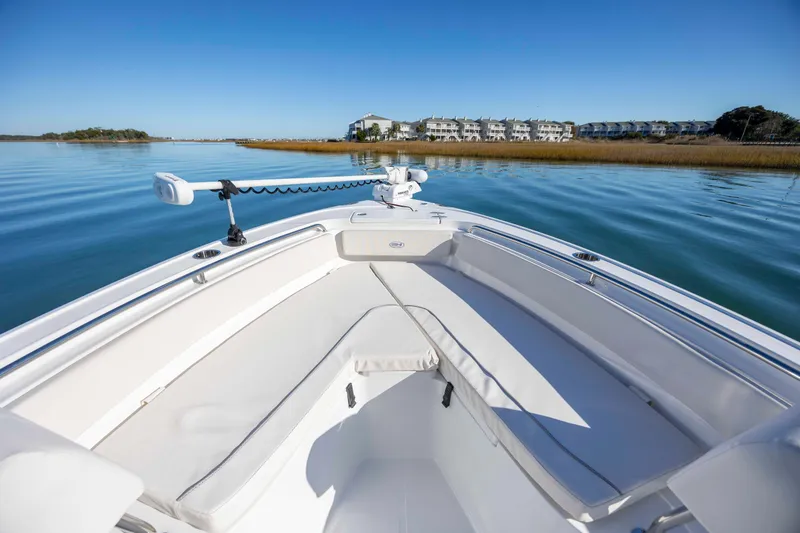 Slide: The Image of 2024 Sea Hunt Ultra 239 SE boat on calm water with scenic shoreline view. - 9