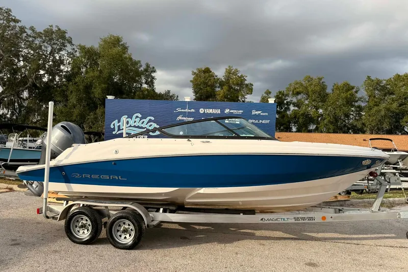 The Image of 2023 Regal 21 OBX boat on trailer, blue and white design, outdoor setting. - 0