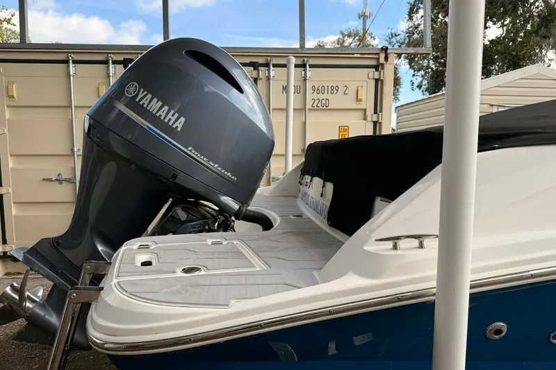Slide: The Image of 2023 Regal 21 OBX boat with Yamaha outboard motor, docked near storage containers. - 16