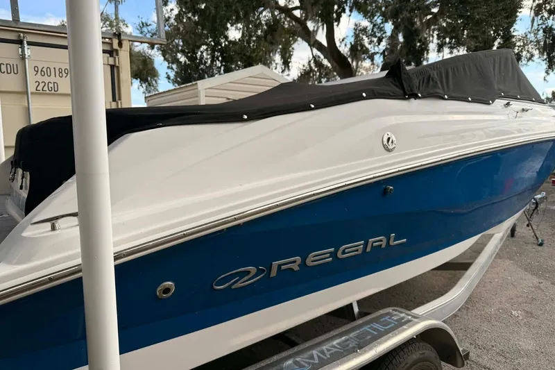 Slide: The Image of 2023 Regal 21 OBX boat with blue and white hull on a trailer. - 2