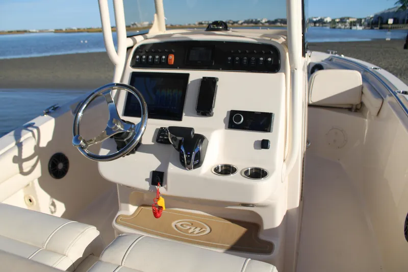 Slide: The Image of 2024 Grady-White Fisherman 216 boat console with steering wheel and controls, docked by the water. - 18