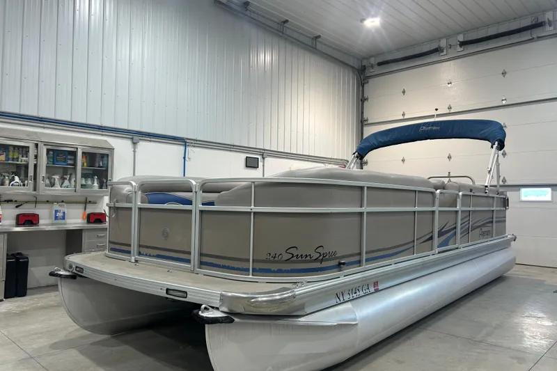 The Image of 2009 Premier 240 SunSpree pontoon boat in a garage, featuring a blue canopy. - 0