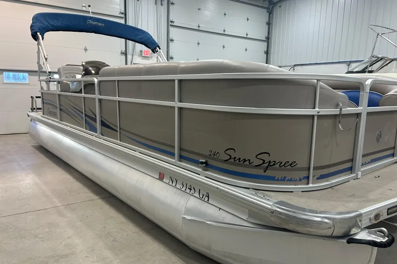 Slide: The Image of 2009 Premier 240 SunSpree pontoon boat in a garage, featuring blue accents and a canopy. - 22