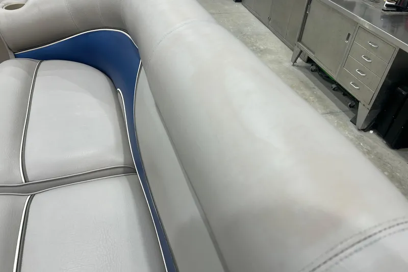 Slide: The Image of 2009 Premier 240 SunSpree boat interior with gray and blue seating, in a workshop setting. - 28