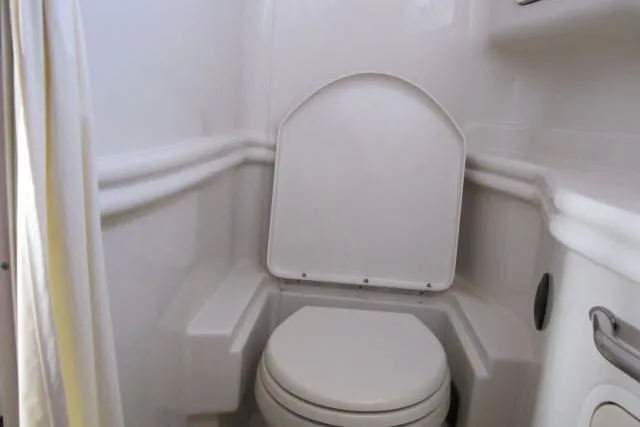 Slide: The Image of 2007 Sea Ray 340 Sundancer boat bathroom with compact toilet and white interior. - 17