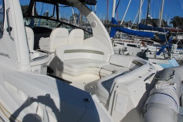 Slide: The Image of 2007 Sea Ray 340 Sundancer boat interior with white seating and marina background. - 20