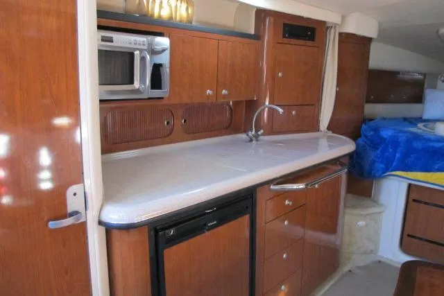 Slide: The Image of 2007 Sea Ray 340 Sundancer interior with kitchenette, featuring wood cabinetry and modern appliances. - 5