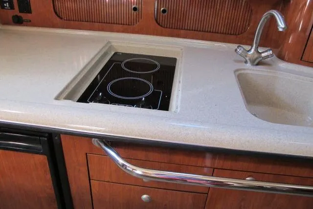 Slide: The Image of 2007 Sea Ray 340 Sundancer kitchen with stove, sink, and wooden cabinetry. - 6