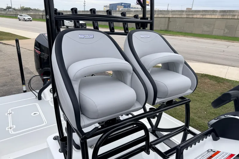 Slide: The Image of 2026 SCB R24 boat with dual gray seats and black trim, parked outdoors. - 14