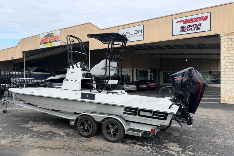 Slide: The Image of 2026 SCB R24 boat on trailer outside dealership, featuring powerful outboard motor. - 2
