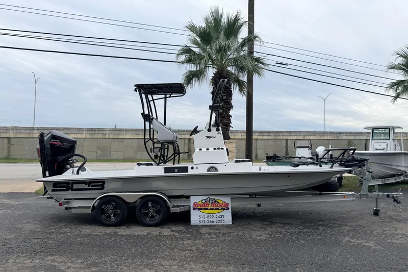 Slide: The Image of 2026 SCB R24 boat on trailer, parked outdoors near palm trees. - 40