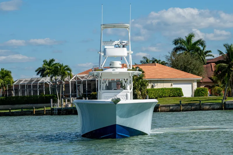 Slide: The Image of 2018 Yellowfin 36 Offshore boat cruising near waterfront homes, under a clear blue sky. - 45