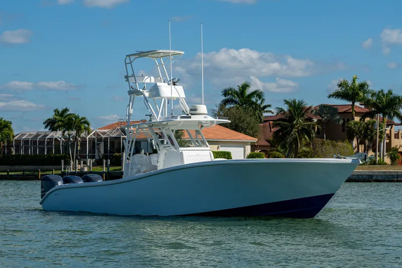 Slide: The Image of 2018 Yellowfin 36 Offshore boat on water, with palm trees and houses in the background. - 48