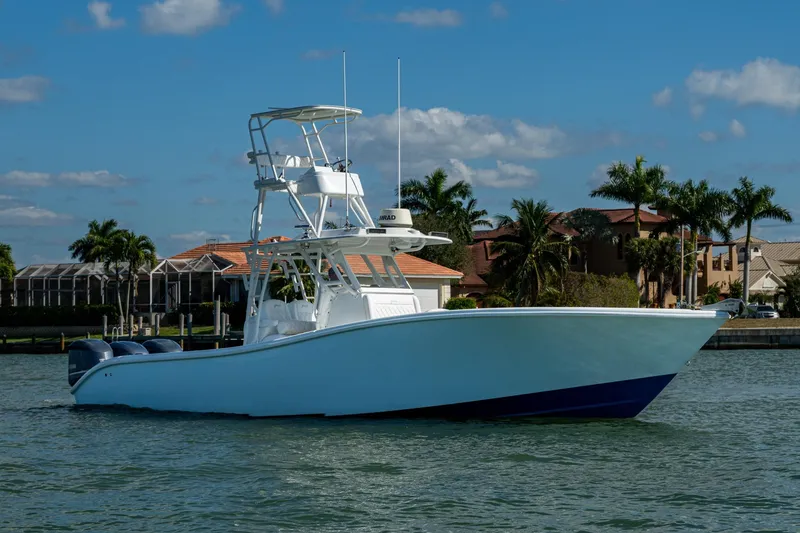 Slide: The Image of 2018 Yellowfin 36 Offshore boat on water, with palm trees and houses in the background. - 49