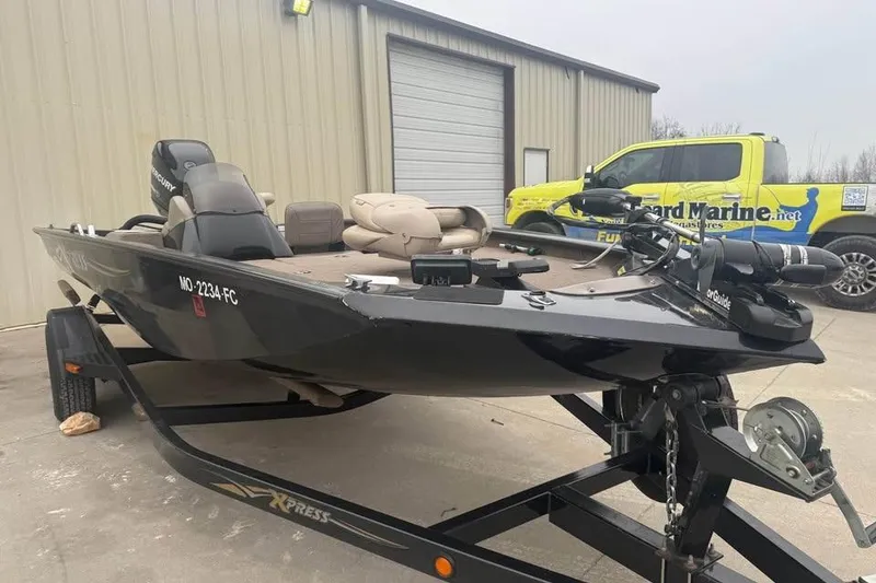 Slide: The Image of 2004 Express x17 boat on trailer, parked near a building and a branded truck. - 3