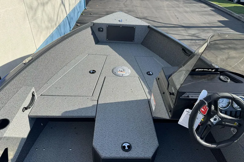 Slide: The Image of 2026 Lund 1675 Adventure SS boat interior with steering wheel and storage compartments. - 12