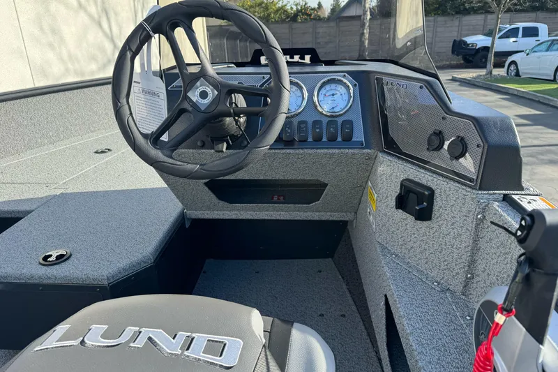 Slide: The Image of 2026 Lund 1675 Adventure SS boat interior with steering wheel and dashboard controls. - 8