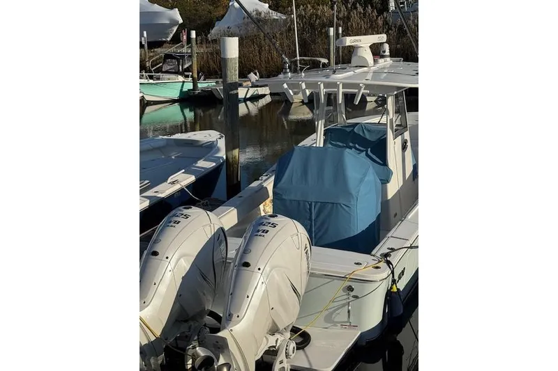 Slide: The Image of 2023 Regulator 31 boat docked with twin outboard engines and blue cover. - 4