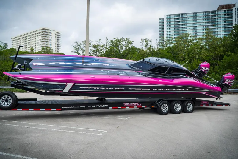 The Image of 2023 MTI 390XR powerboat with vibrant pink and black design on a trailer. - 0