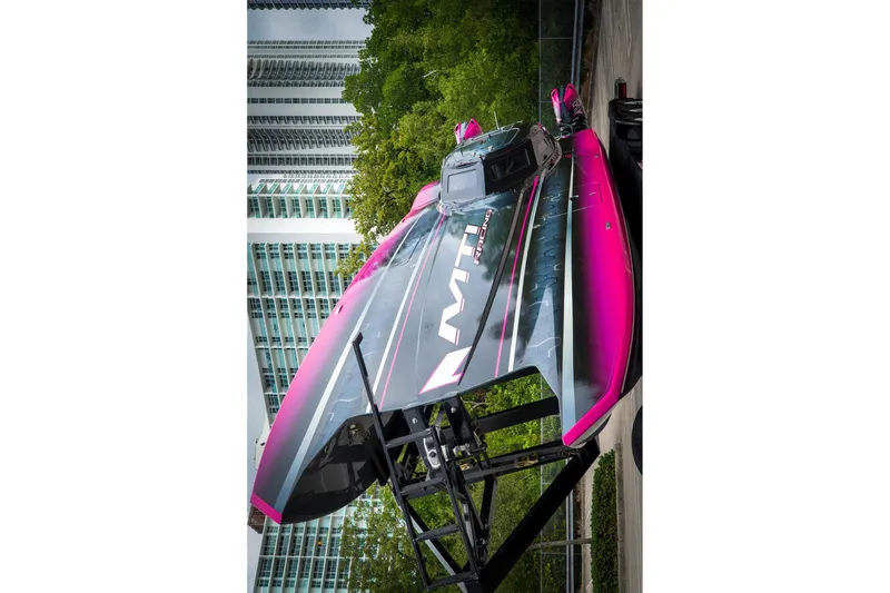 Slide: The Image of 2023 MTI 390XR powerboat with vibrant pink and black design, displayed outdoors. - 10
