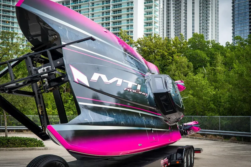 Slide: The Image of 2023 MTI 390XR racing boat on trailer, vibrant pink and black design, urban background. - 11